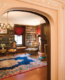 Off the living room, the walnut paneled library incorporates built-in window seats and shelving holding books in Russian and English. The oriental rug and tapestry-upholstered bergere are typical of the furnishings throughout the house.